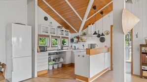 A modern kitchen with white cabinets, wooden flooring, and a central island. - 1 bedroom awesome home in Jægerspris (Jægerspris)