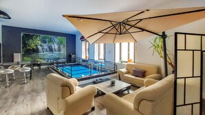 Un espace de détente moderne doté d’une table de billard, de sièges confortables et d’un grand écran diffusant une vidéo d’une cascade.