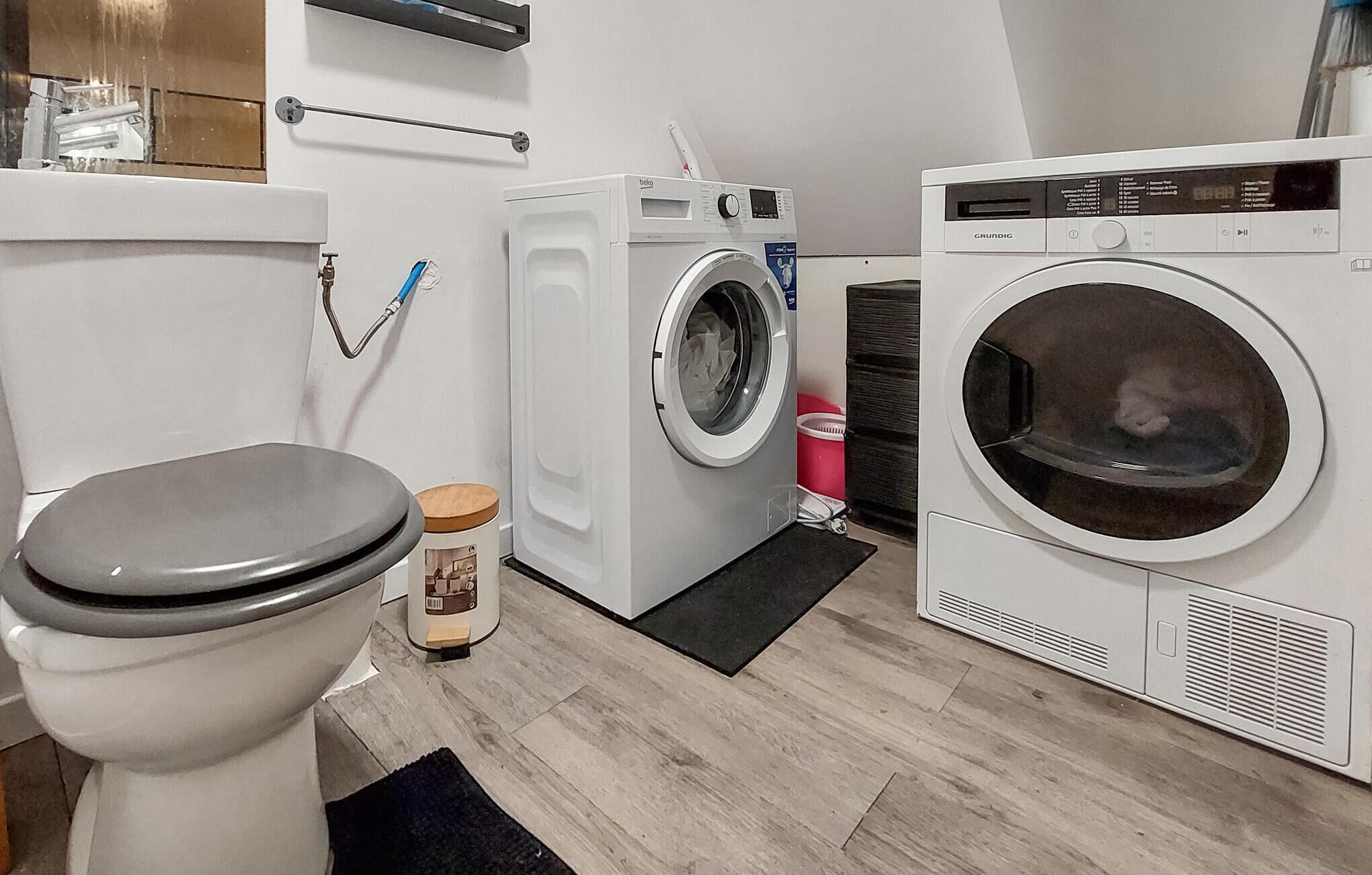 Et lille vaskerum med vaskemaskine, tørretumbler og toilet.