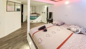 Une chambre à coucher avec un lit, une télévision et une salle de bain visible à travers une porte ouverte.