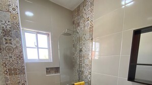 Une salle de bain avec une douche, des toilettes, un lavabo et une fenêtre.