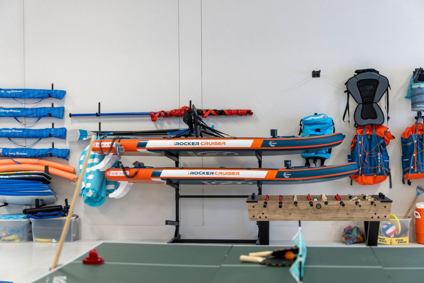 Une pièce contenant deux kayaks iRocker Cruiser, une planche de paddle et divers équipements pour le kayak.