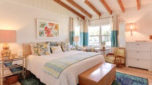 A bedroom with a large bed, a wooden bench, a nightstand, a lamp, a chair, a desk, and a dresser. - Pet-Friendly Home ~ 6 Mi to Jensen Beach Park! (Jensen Beach)