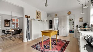 A modern kitchen with white cabinets, a wooden table, and a red patterned rug. - Stunning home in Vestervig with WiFi (Vestervig)