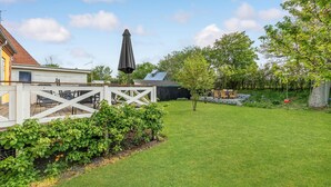 A backyard with a white fence, a covered patio area, and a lawn. - Stunning home in Vestervig with WiFi (Vestervig)