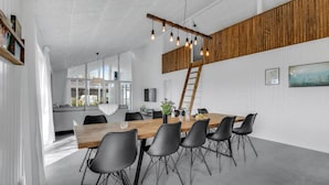 A modern dining area with a wooden table, black chairs, and a hanging light fixture. - Beautiful home in Nexø with kitchen (Nexø)