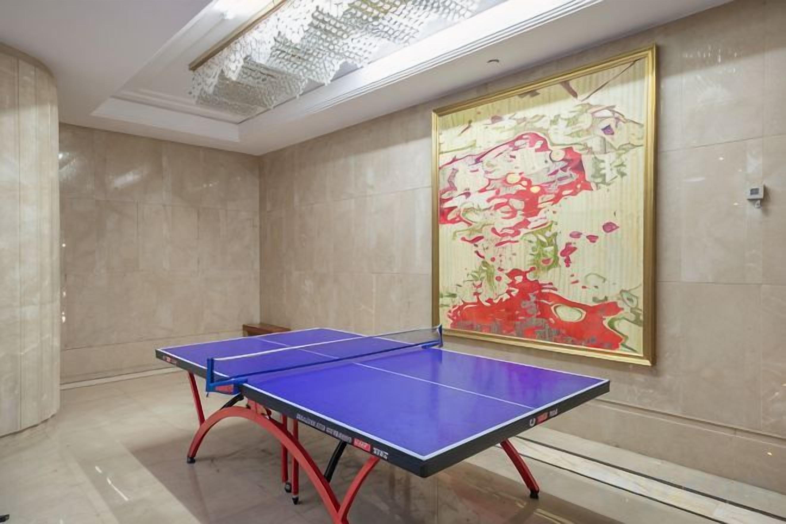 Una mesa de ping pong en una habitación con un cuadro abstracto grande en la pared.