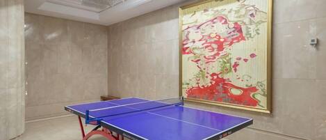 Una mesa de ping pong en una habitación con un cuadro abstracto grande en la pared.