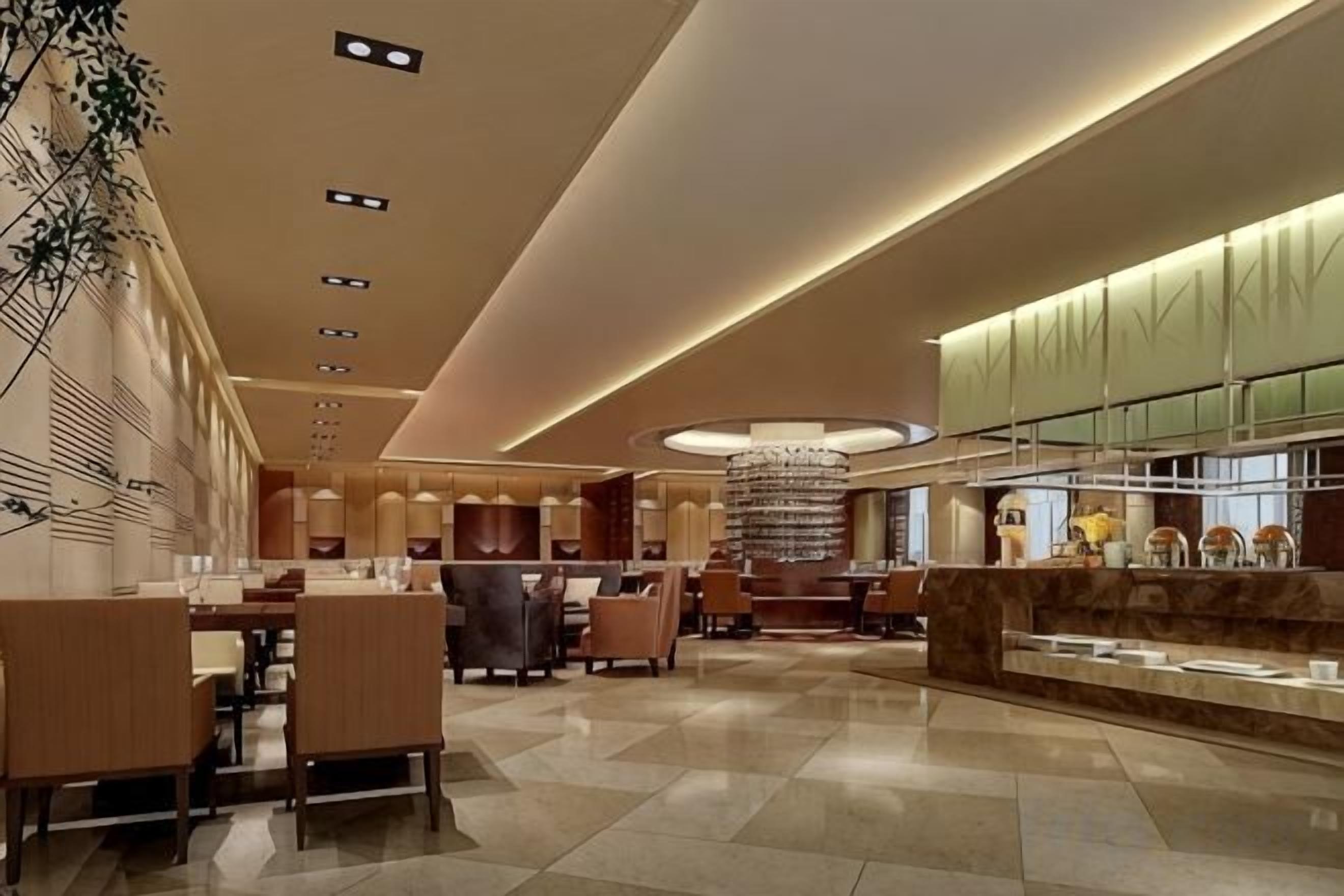 A spacious lobby with a central seating area, a reception desk, and a chandelier.