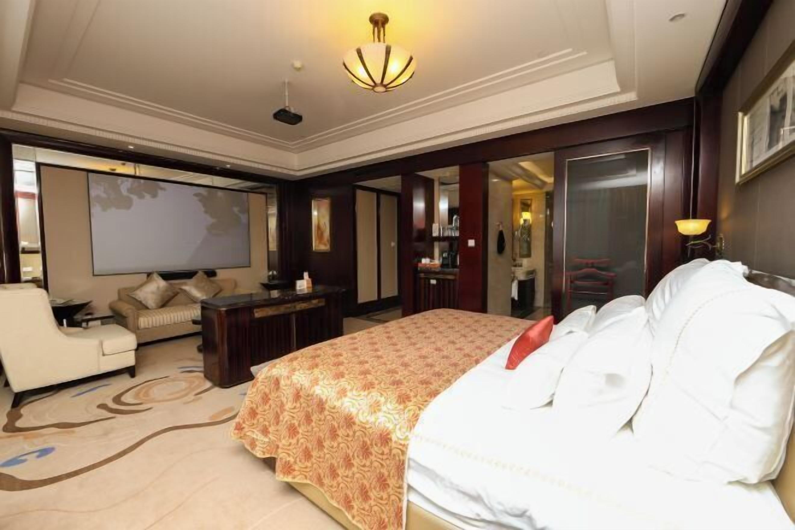 A hotel room with a large bed, a sofa, a desk, and a television.