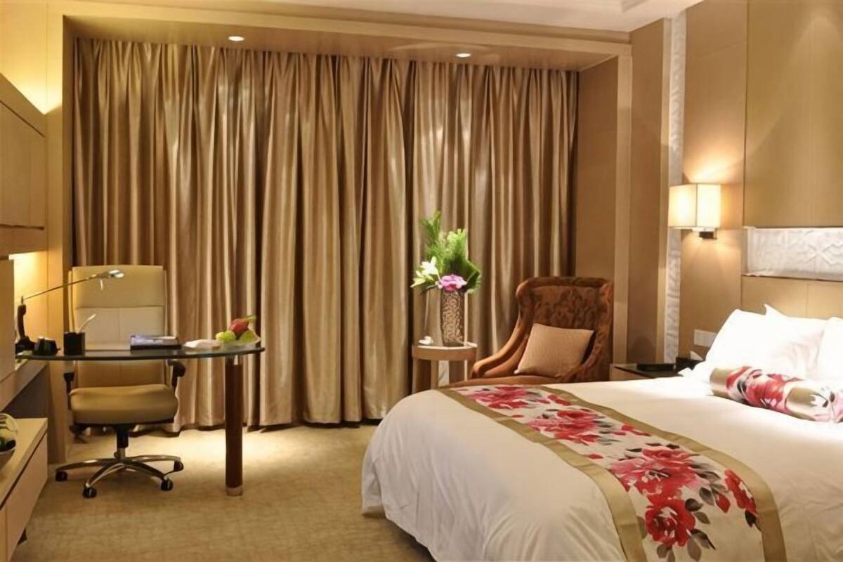 Habitación de hotel con cama, escritorio, silla y cortinas.