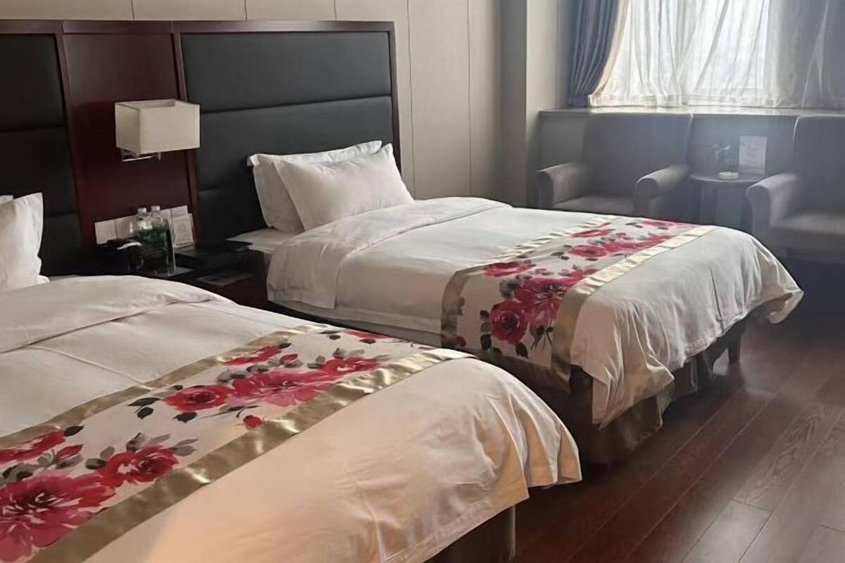 Habitación de hotel con dos camas, una mesita de noche, un escritorio y una silla.