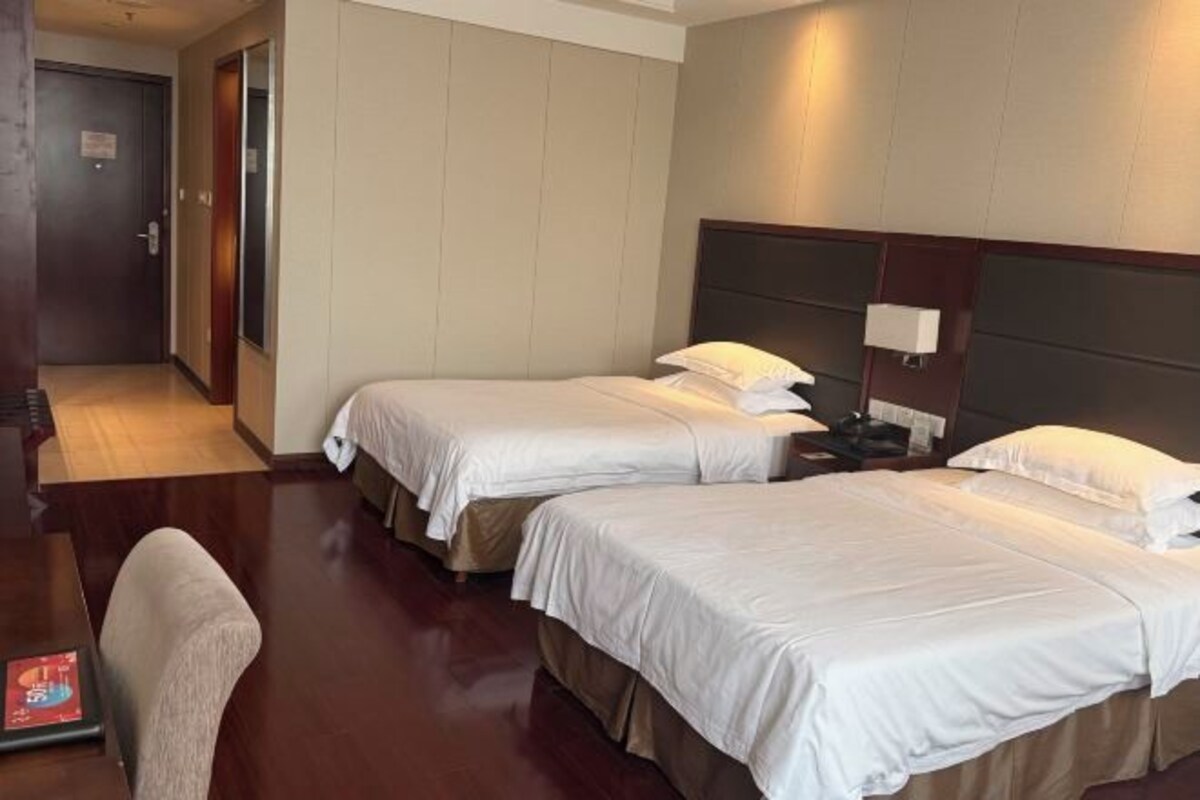 A hotel room with two beds, a desk, and a chair.