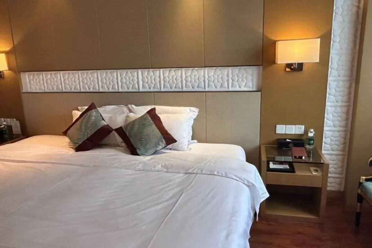 Habitación de hotel con una cama grande, una mesita de noche, una lámpara y un escritorio pequeño.