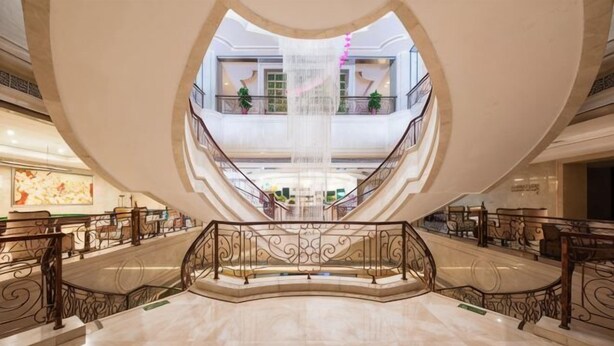 A spacious atrium with a central water feature, multiple floors, and ornate railings. - Mingdu Hotel (Zhenjiang)