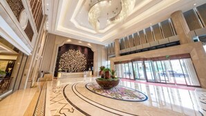 A spacious lobby with a central reception desk, a chandelier, and a large window with a view of the outside. - Mingdu Hotel (Zhenjiang)