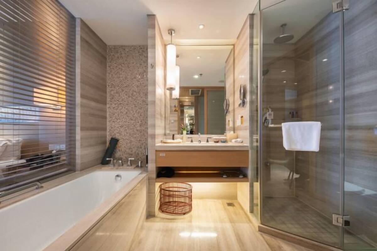 Un baño moderno con cabina de ducha de vidrio, una bañera grande y un mueble de tocador con espejo.