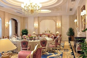 Un comedor formal con candelabro, sillas ornamentadas y una larga mesa dispuesta para una comida.