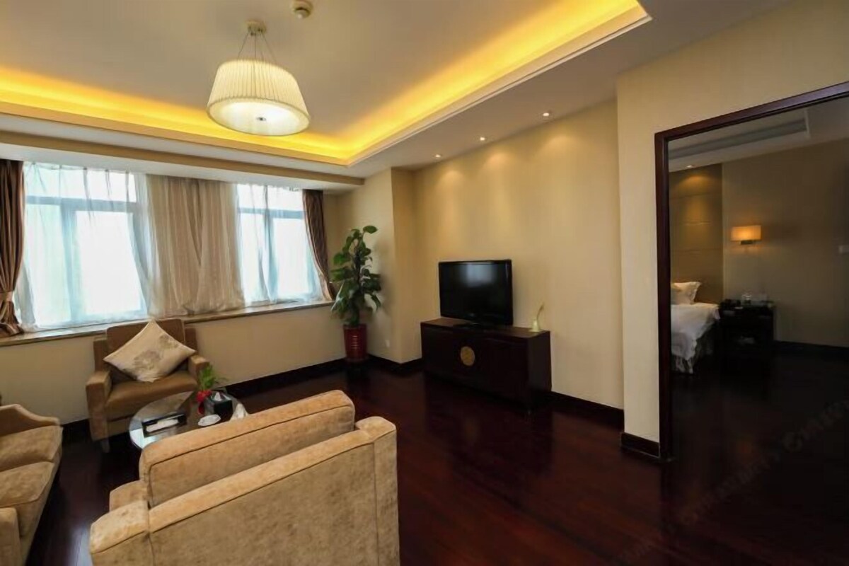 A modern hotel room with a sofa, television, and a plant.