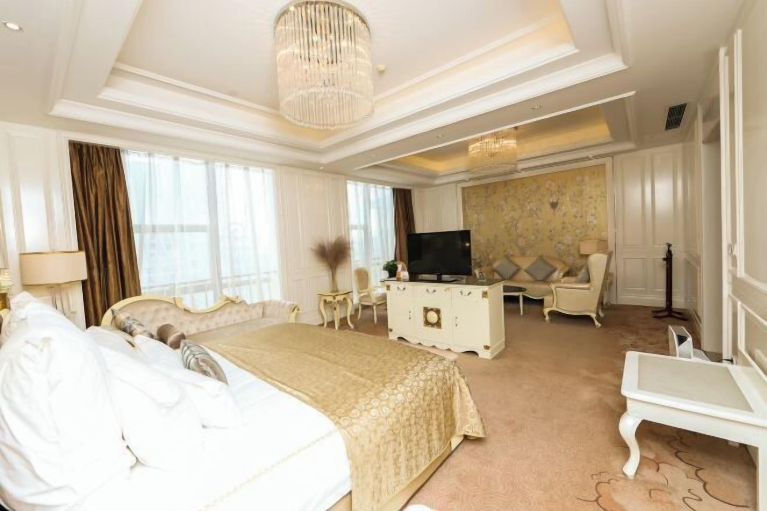 Habitación de hotel con una cama grande, televisión, escritorio y una silla.