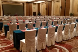 A conference room with rows of tables and chairs, a stage, and a carpeted floor. - Mingdu Hotel (Zhenjiang)