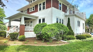 A two-story house with a front porch, a balcony on the second floor, and a well-maintained garden.