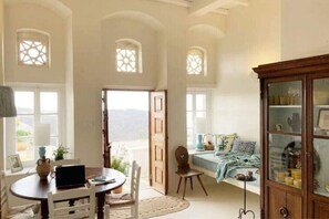 Una habitación con una mesa redonda, sillas, un armario y una ventana con vistas.