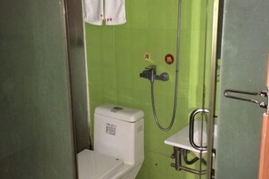 A small bathroom with a toilet, a shower, and a sink.