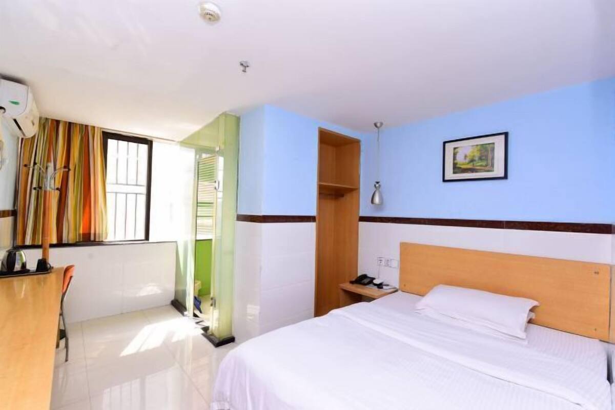 Una habitación de hotel con cama, escritorio, teléfono y un cuadro en la pared.