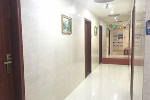 A corridor with marble walls, wooden doors, and a tiled floor.