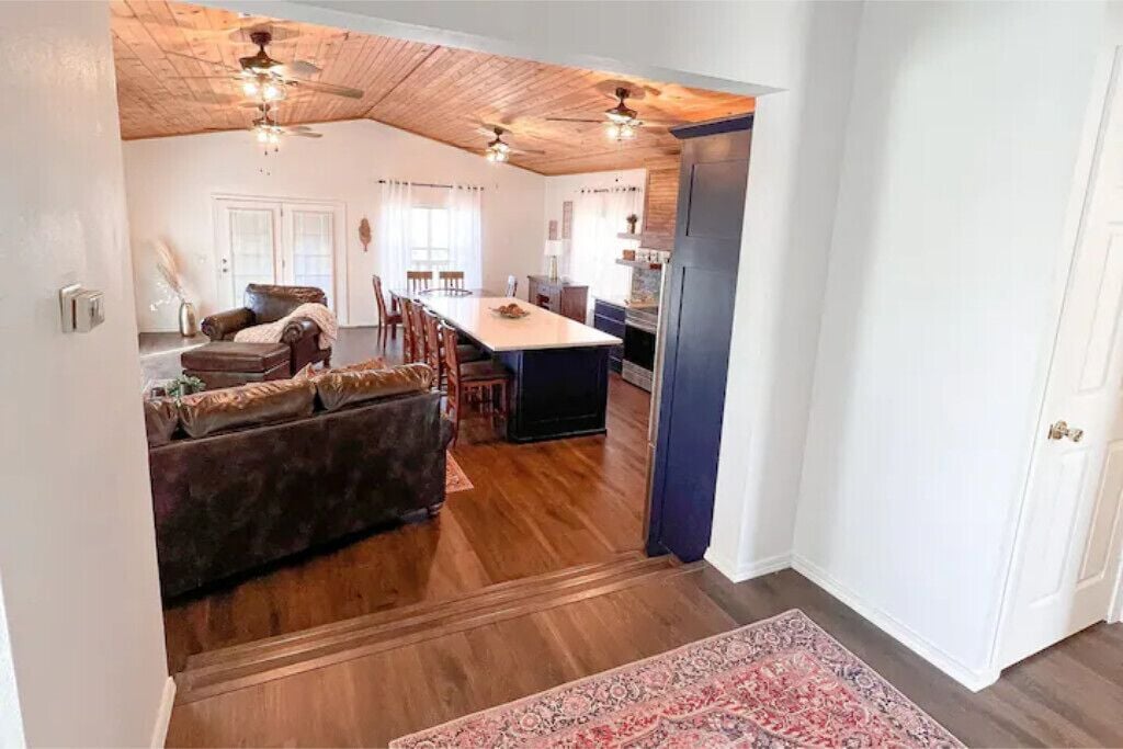 Un espacio habitable amplio con un sofá grande, una mesa de comedor y una cocina al fondo.