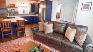 A living room with a brown leather sofa, a wooden coffee table, and a patterned rug. - PERFECT GETAWAY cabin near Turner Falls & Lake of The Arbuckles. (Sulphur)
