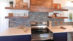 A modern kitchen with a built-in oven, wooden cabinets, and a stone backsplash. - PERFECT GETAWAY cabin near Turner Falls & Lake of The Arbuckles. (Sulphur)