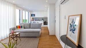 A modern living room with a grey sofa, a small round table, and a framed artwork on the wall. - Pestana Apartments T1 Terrace  (Porto)