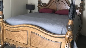Una cama de madera con dosel, un tablero auxiliar y una lámpara.