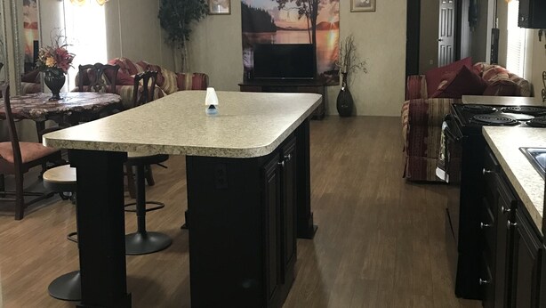 Una cocina amplia con una isla central, armarios de madera y un comedor con sillas y una mesa.