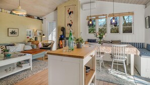Una sala de estar acogedora con chimenea, un comedor con mesa de madera y una cocina con estufa.