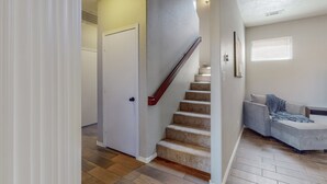 Un escalier dont les marches sont recouvertes de moquette et qui possède une main courante en bois, menant à une porte.