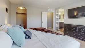 Une chambre à coucher avec un lit, une commode, une télévision et un dressing.