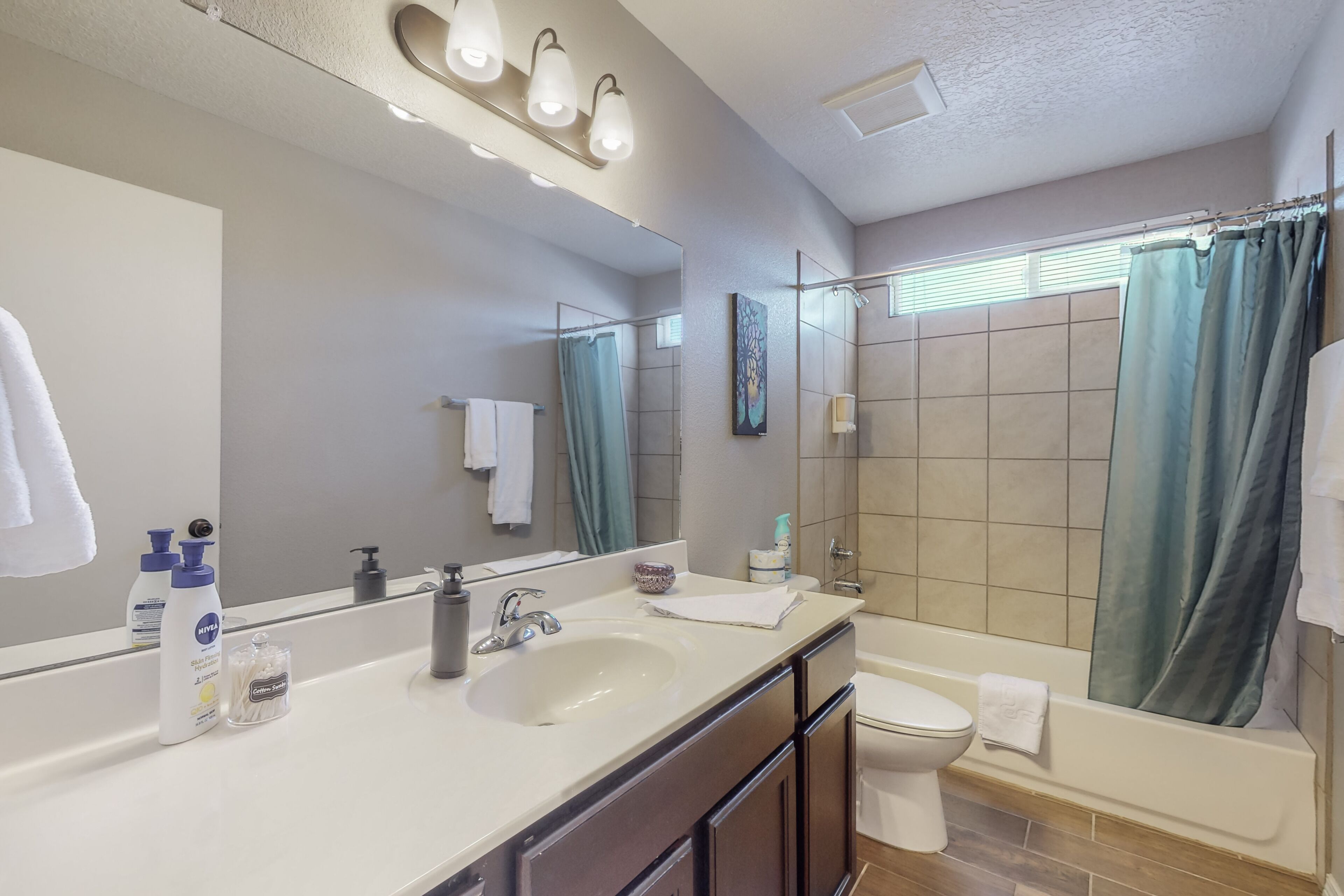 A modern bathroom with a double sink, a large mirror, a shower with a curtain, and a toilet.