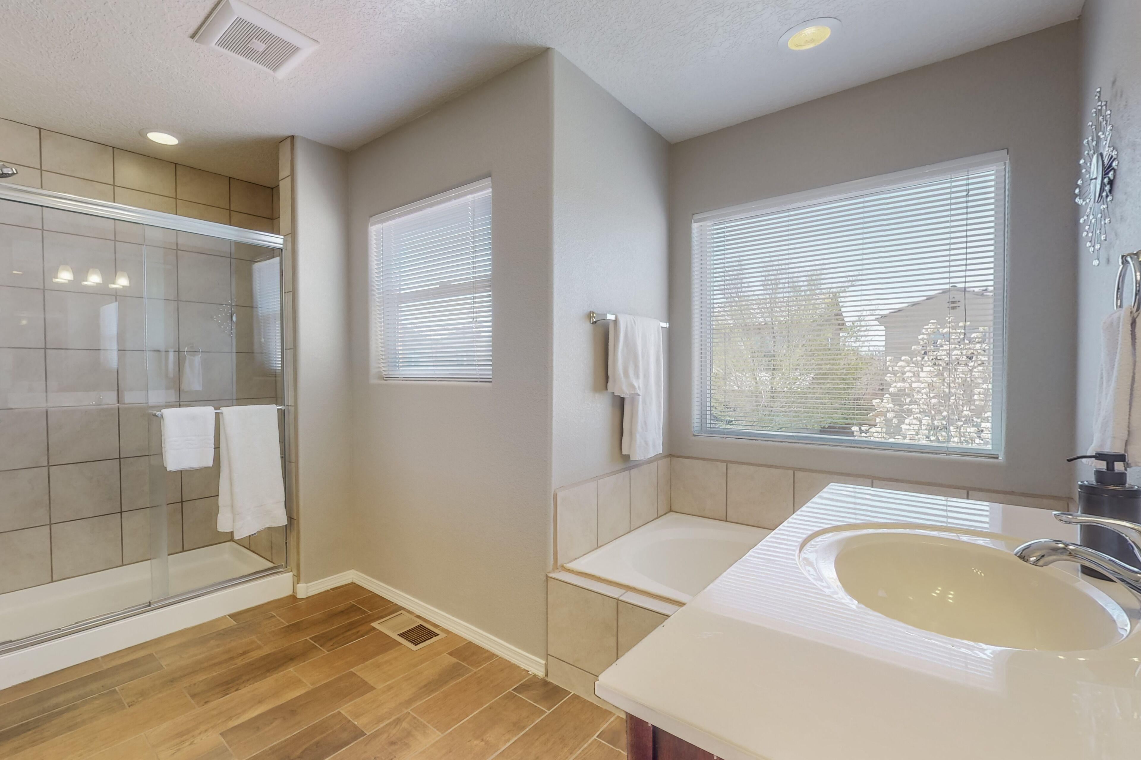 A modern bathroom with a glass shower, a bathtub, and a sink.