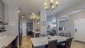 Une cuisine moderne avec un coin repas, comprenant un îlot central, des appareils électroménagers intégrés et un lustre.