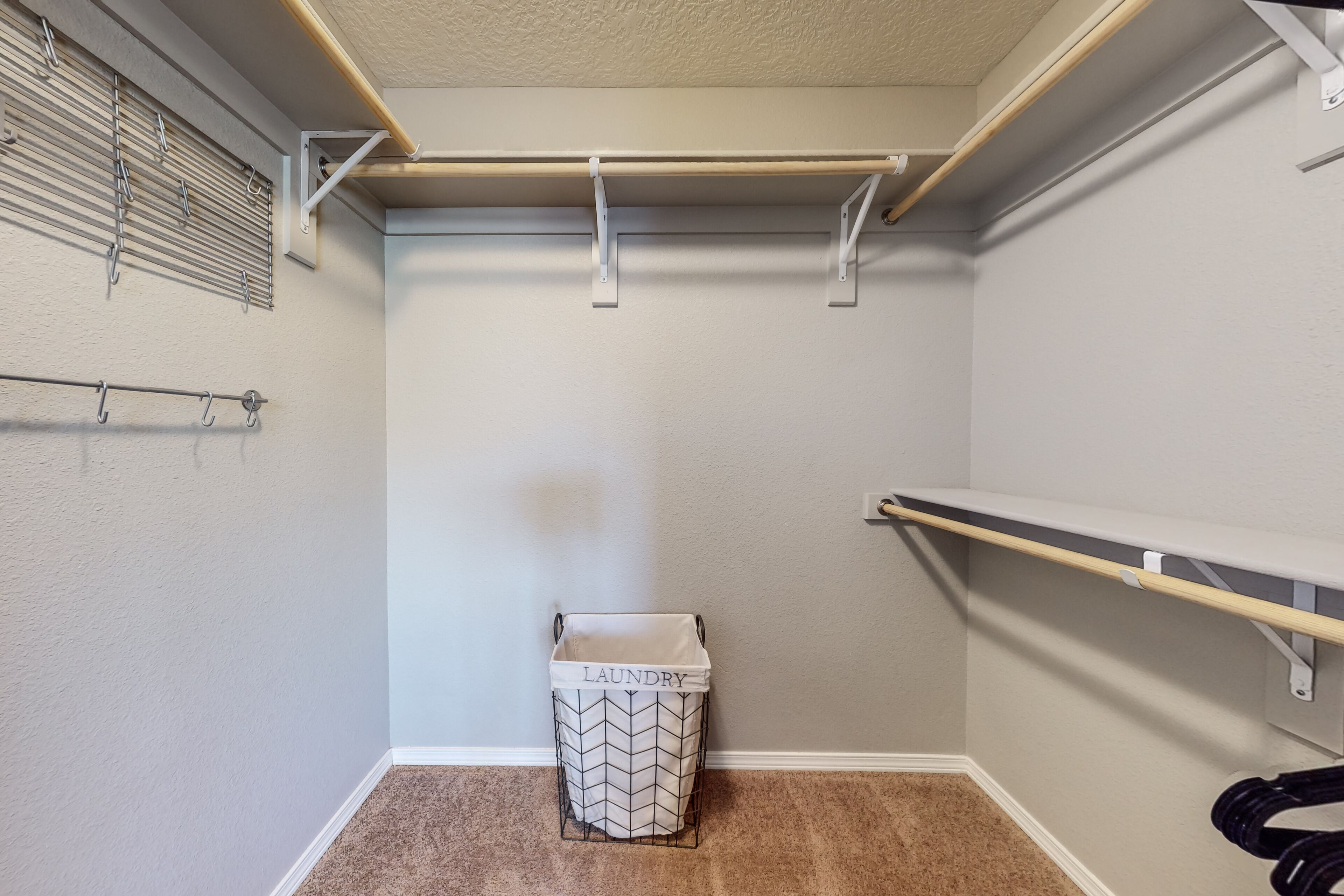 A laundry room with a metal rack, a laundry basket, and a shelf.
