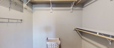 A laundry room with a metal rack, a laundry basket, and a shelf.