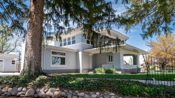 A modern two-story house with a stone retaining wall, a covered porch, and a well-maintained lawn. - Charming Historic Home with chef's kitchen formal dining, sitting room, & patio (Payson)
