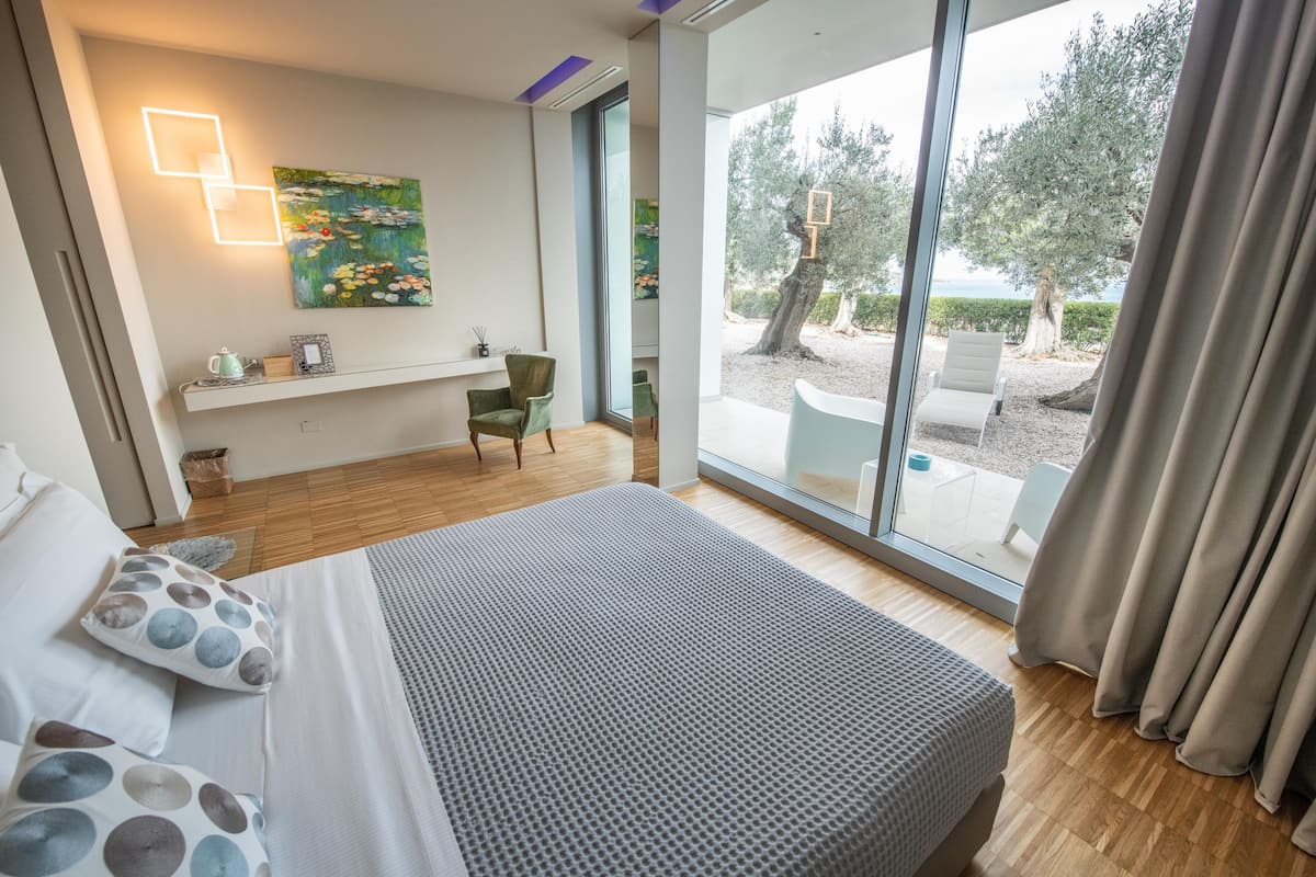 Une chambre moderne avec un grand lit, un bureau et une vue sur l’extérieur.