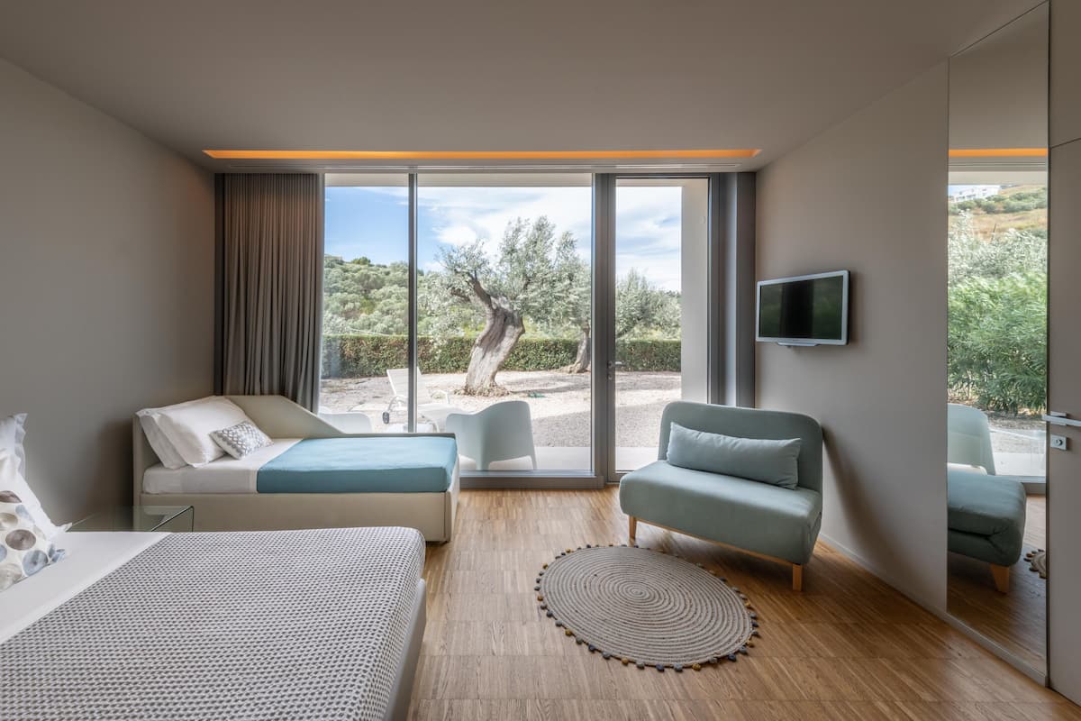 Une chambre d’hôtel moderne équipée d’un lit, d’un canapé, d’un fauteuil et d’une télévision.