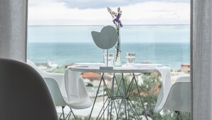 Une table ornée d’un vase de fleurs et de deux verres, le tout placé devant une vue sur la mer.