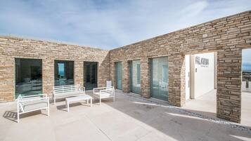 A modern building with a stone facade, large windows, and outdoor seating.