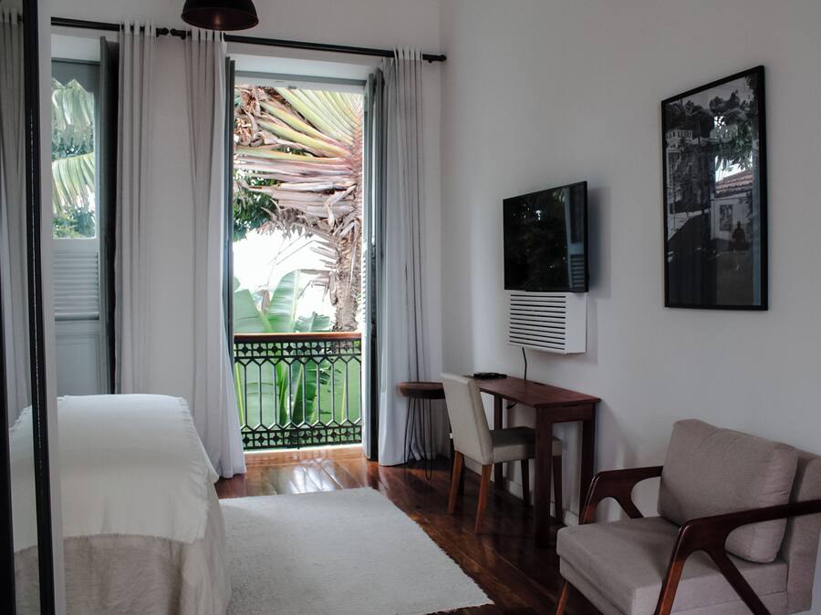 A room with a bed, a desk, a chair, and a TV on the wall.